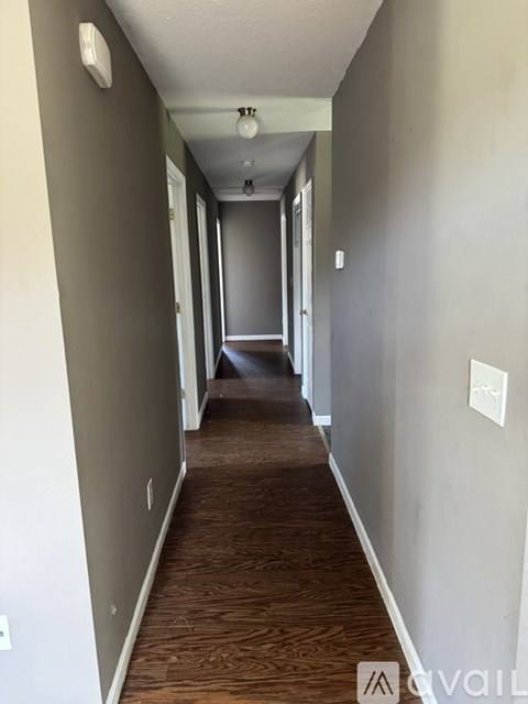 A long hallway with wood floors and white walls.