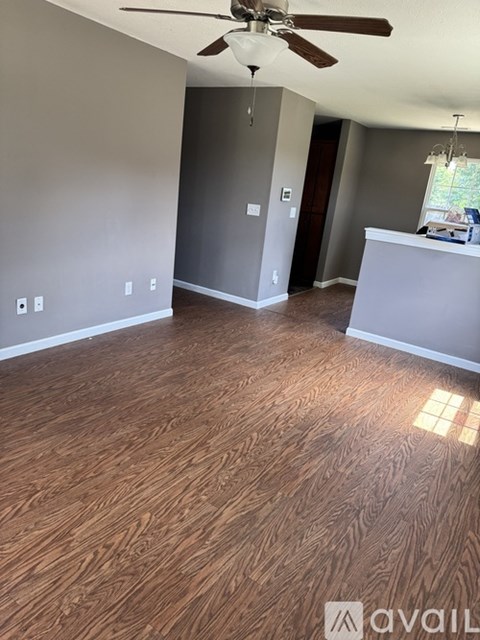 A room with a ceiling fan and wooden flooring.