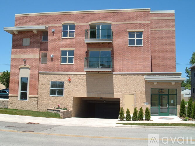 A red brick building with a garage door and a balcony on the second floor.