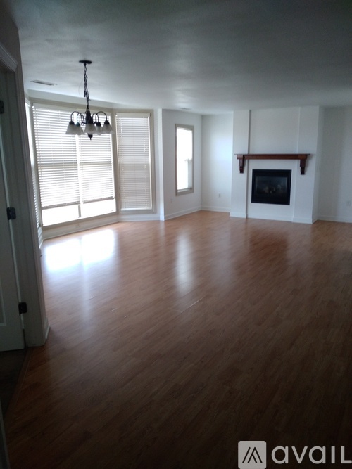 A large empty room with wooden floors and a fireplace.