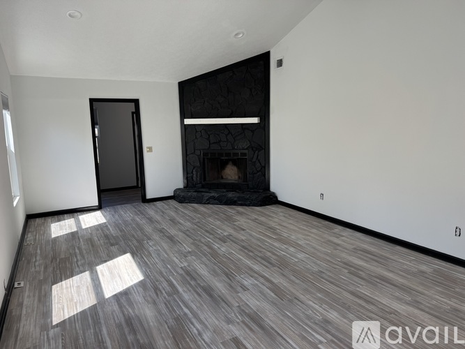 A spacious room with a fireplace and wooden flooring.