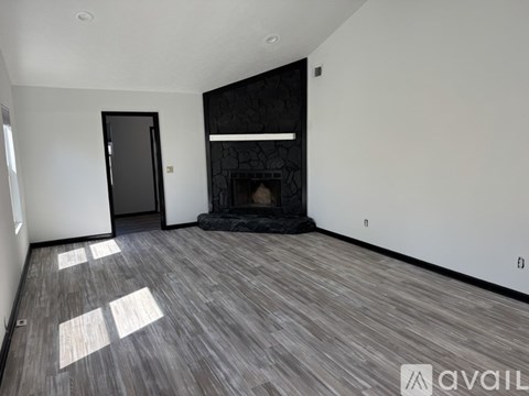 A spacious room with a fireplace and wooden flooring.