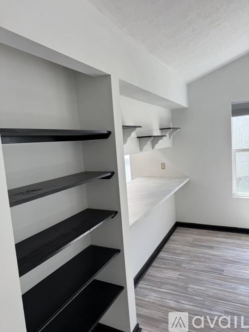 A white wall with a window and a shelf with black and white shelves.