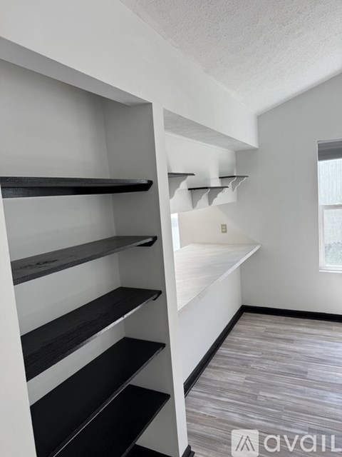 A white wall with a window and a shelf with black and white shelves.