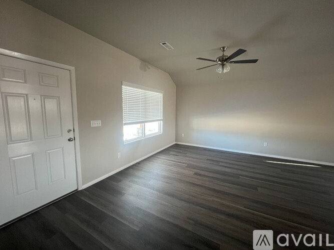 A room with a ceiling fan and wooden flooring.
