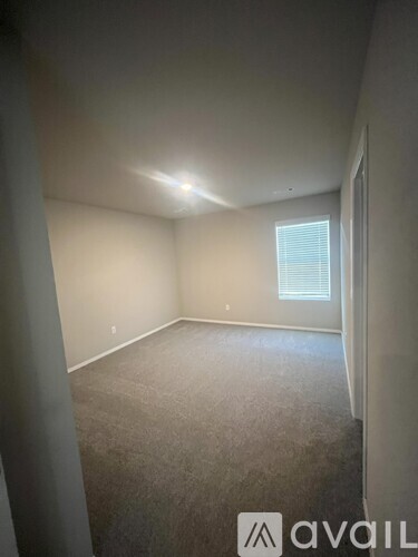 A room with a carpeted floor and a window with blinds.