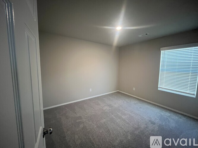 A room with a carpeted floor and a window with blinds.