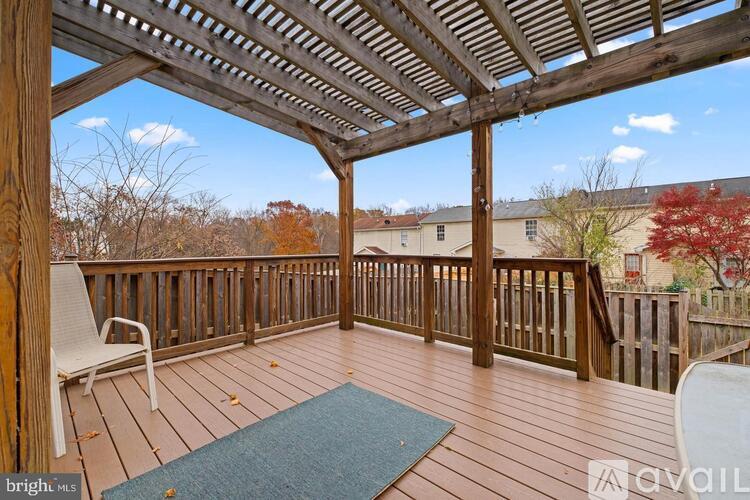 A wooden deck with a pergola and a blue rug.