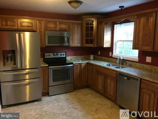 A kitchen with wooden cabinets and a stainless steel refrigerator.