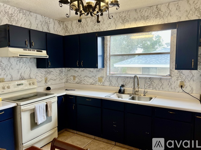 A kitchen with a white stove top oven and a white sink.
