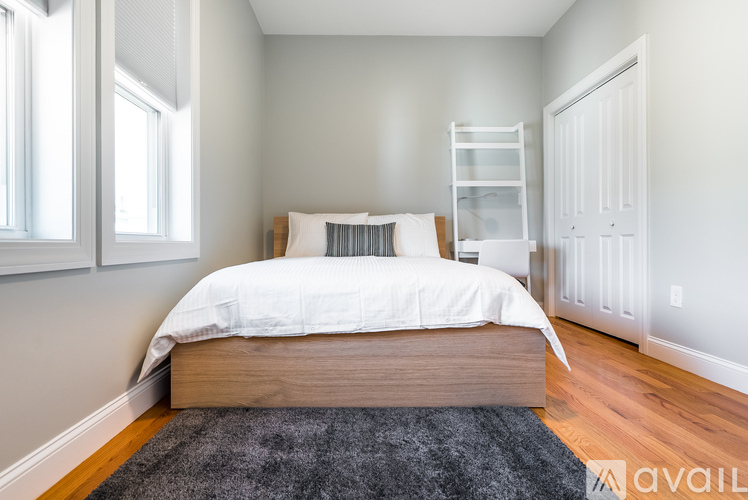 A bedroom with a large bed and a rug on the floor.