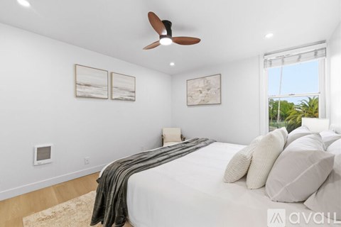 A bedroom with a large bed and a ceiling fan.
