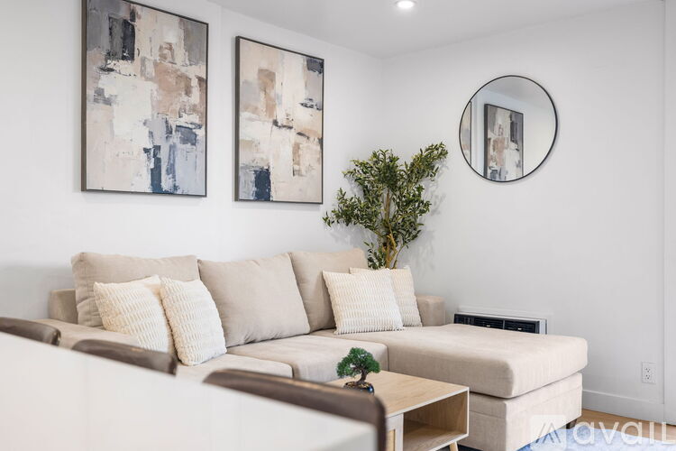 A living room with a white couch and two abstract paintings on the wall.