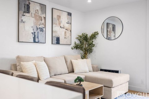 A living room with a white couch and two abstract paintings on the wall.