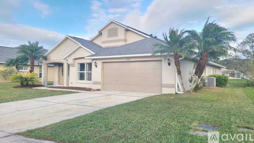 A house with a garage and palm trees in front.