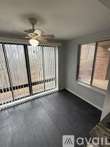 A room with a ceiling fan and a window with blinds.