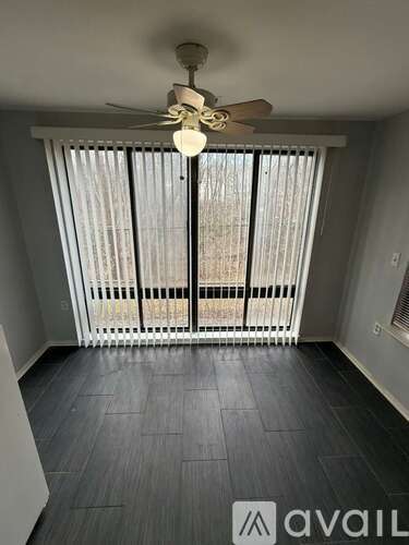 A room with a ceiling fan and a window with blinds.
