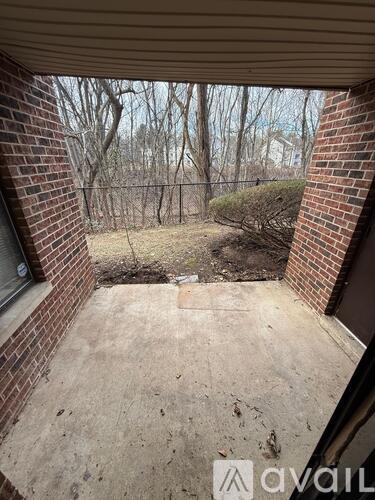 A patio area with a brick wall and a view of trees.