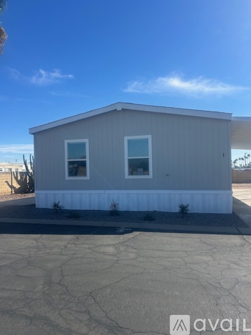 A small house with a grey exterior and two windows is for sale.