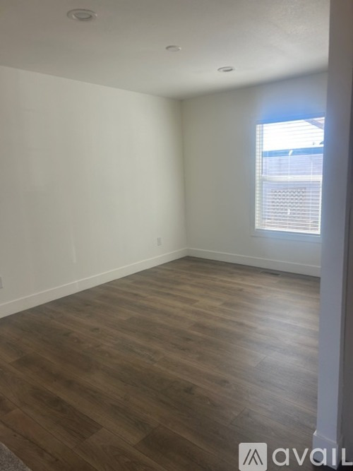 A room with wooden flooring and a window with blinds.