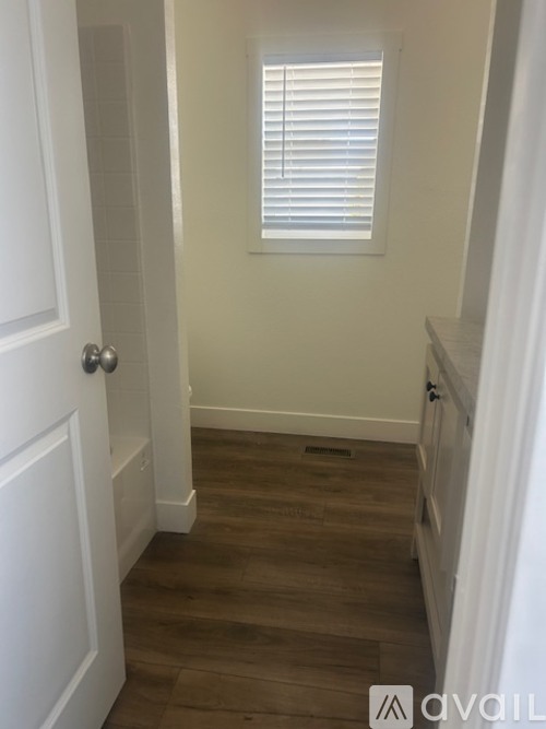 A hallway with a white door and wooden floor.
