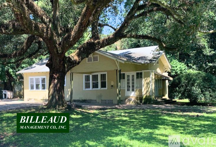 A yellow house with a tree in front of it.