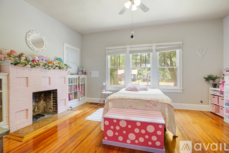 A bedroom with a pink bed and a fireplace.