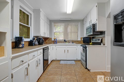 A kitchen with white cabinets and appliances is available for rent.
