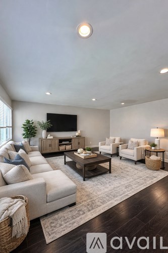 A living room with a large couch, a coffee table, and a flat-screen TV mounted on the wall.