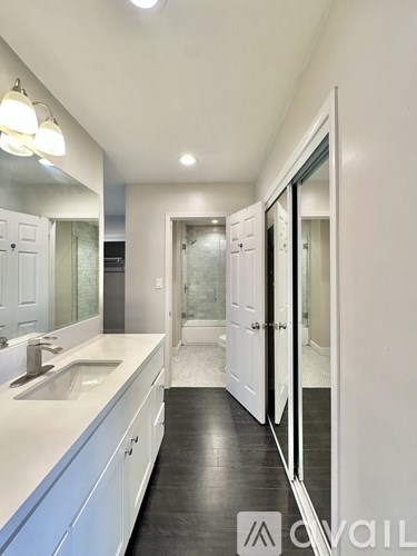 A bathroom with a sink, mirror, and a walk-in shower.