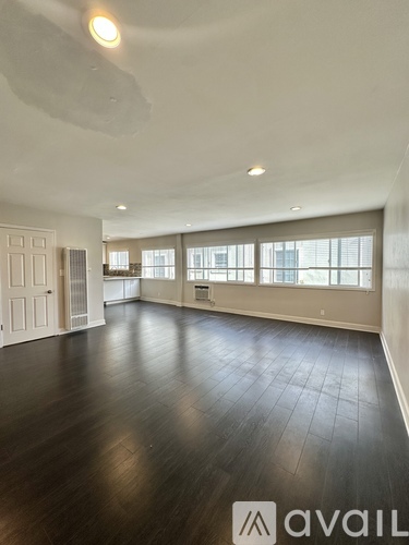 A spacious room with wooden floors and large windows.