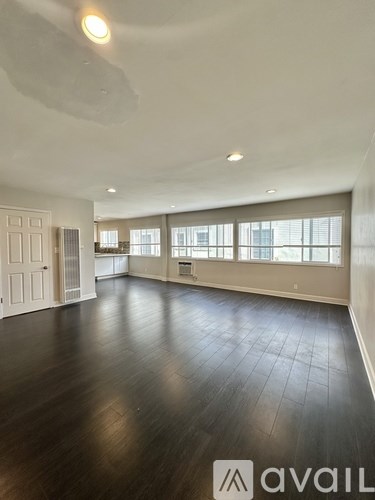 A spacious room with wooden floors and large windows.
