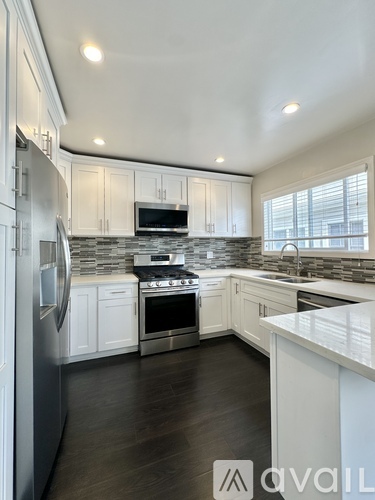 A modern kitchen with white cabinets and stainless steel appliances.