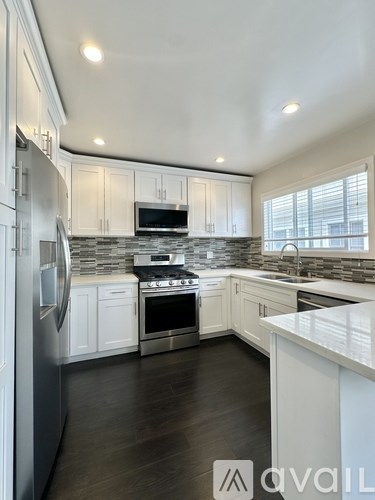 A modern kitchen with white cabinets and stainless steel appliances.