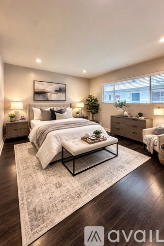 A well-lit bedroom with a large bed and a rug in the center.