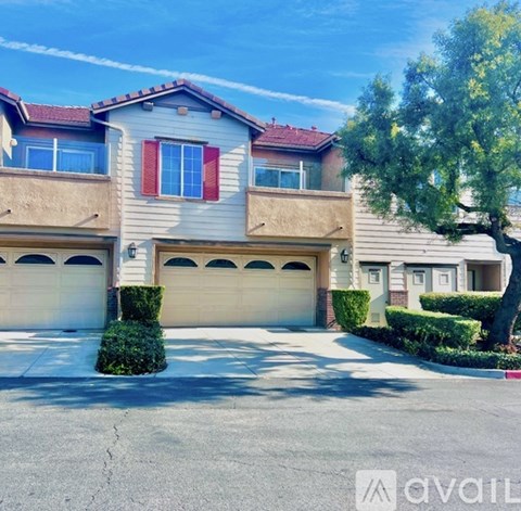 A two-story house with a garage and a tree in front.