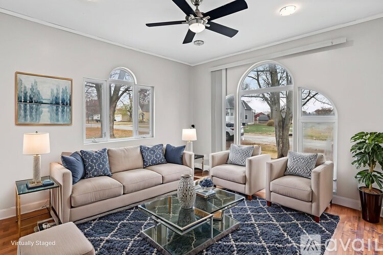 A living room with a beige couch, two chairs, a coffee table, and a ceiling fan.