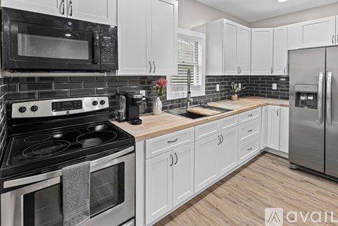 A kitchen with white cabinets and black appliances.