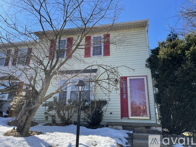 A house with a red door and a tree in front of it.