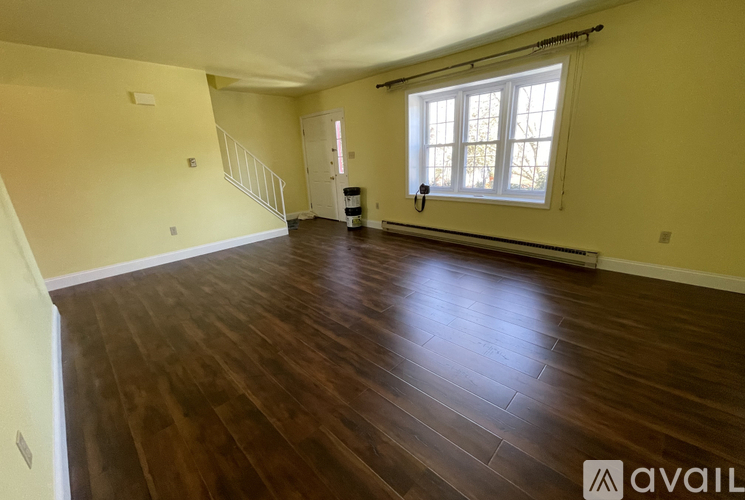 A room with wooden flooring and a window with blinds.