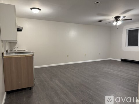 A spacious room with a ceiling fan and a cabinet with a counter on wheels.