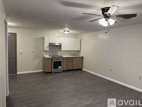 A spacious room with a ceiling fan and a built-in cabinet with a microwave and oven.