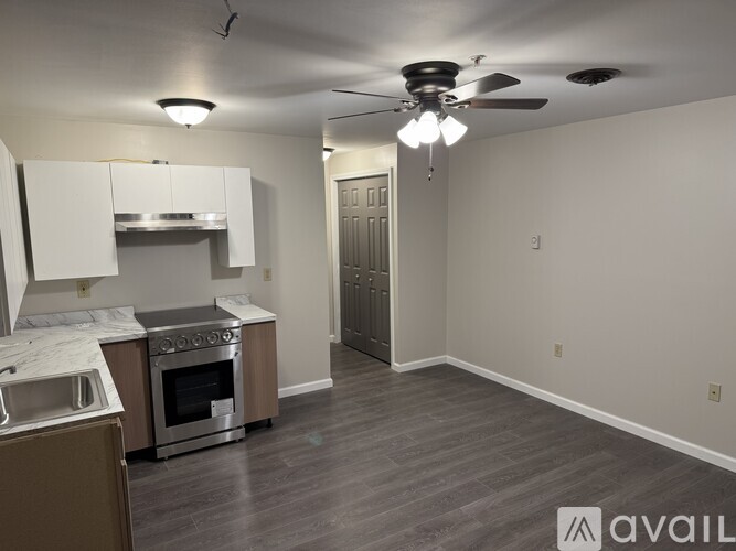 A kitchen with a stove top oven and a fan ceiling light.