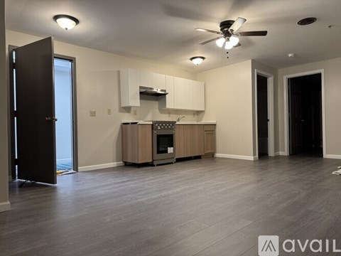 A spacious living room with a kitchenette and hardwood floors.