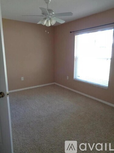 A room with a carpeted floor, a ceiling fan, and a window with blinds.