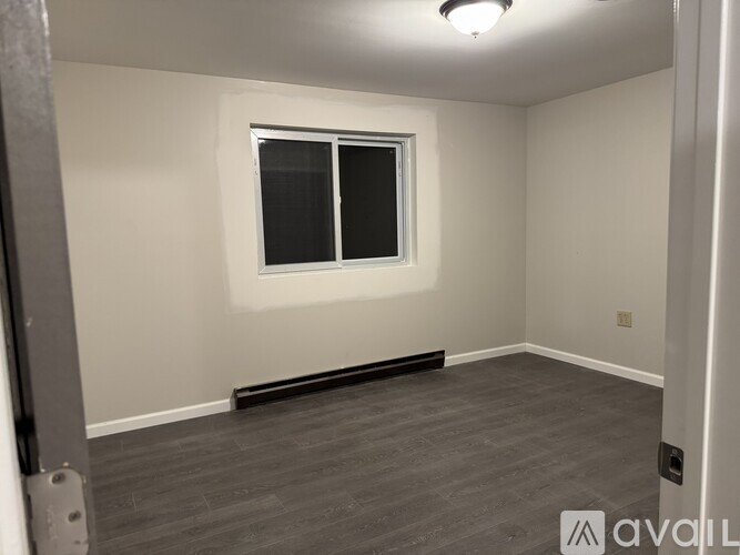 A room with a window and a wooden floor.
