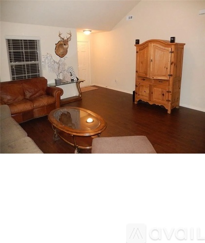 A room with a brown couch, a glass table, and a wooden cabinet.