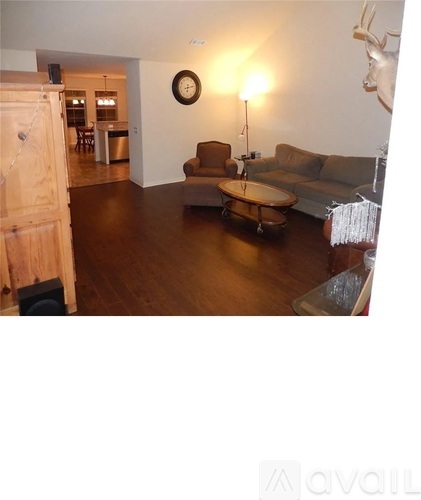 A living room with a couch, chair, and a clock on the wall.