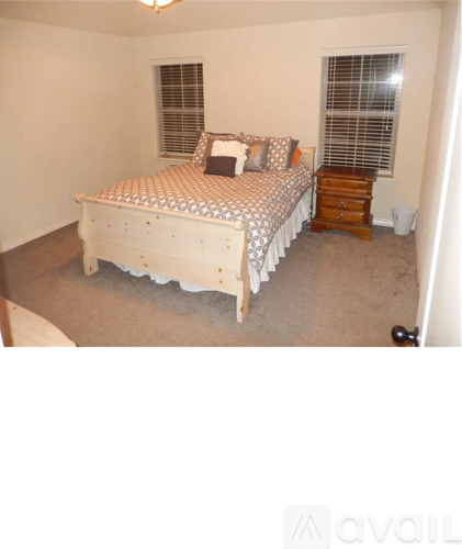 A bedroom with a bed, nightstand, and window.