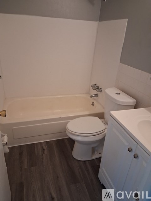 A white toilet sits next to a bathtub in a bathroom.